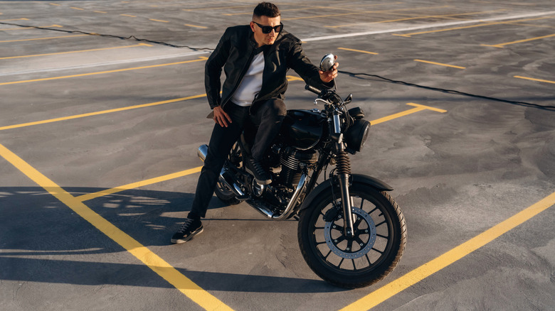 A man sitting on a motorcycle in an empty parking lot.