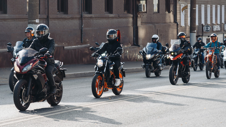 A group of motorcyclists ride together on a street.