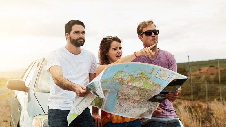 Two men and a female looking astatine a roadworthy map