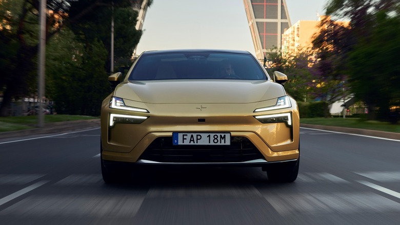 A Polestar 4 in gold from the front, driving through an urban area