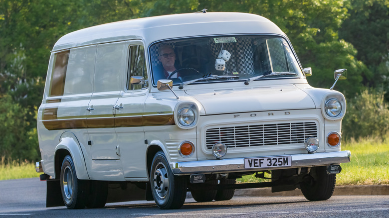 A first-generation Ford Transit V4 Mk1 with someone inside it on a road