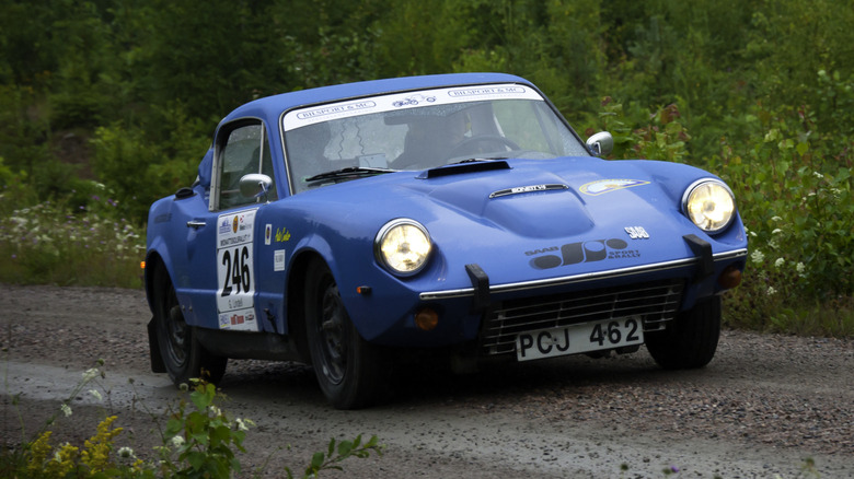 A Saab Sonett II driving down a leafy road