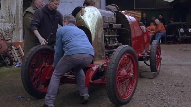 A group of people standing around a Fiat S76 with the Beast of Turin engine on display
