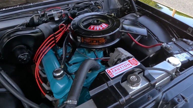 A closeup of the blue-painted 3.2-liter Pontiac Trophy 4 four-cylinder engine topped with a four-barrel carburetor