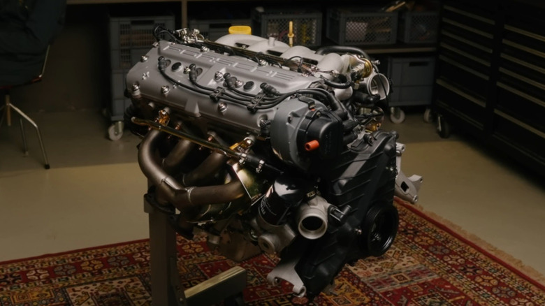 A closeup of a fully restored Porche M44/41 3-liter four-cylinder engine from a Porsche 944 S2, in a workshop, over a multicolored rug