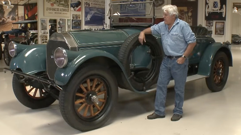 Jay Leno standing near a dark green 1918 Pierce-Arrow Model 66