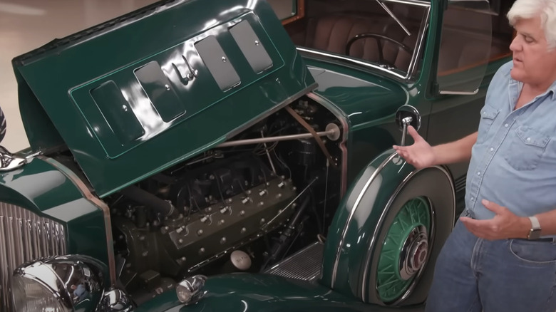 Jay Leno standing next to a Packard Twin Six