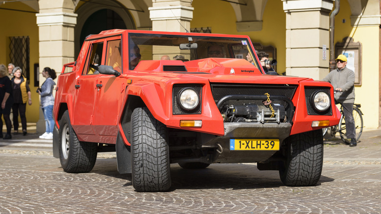 A red Lamborghini LM002 parked outside.