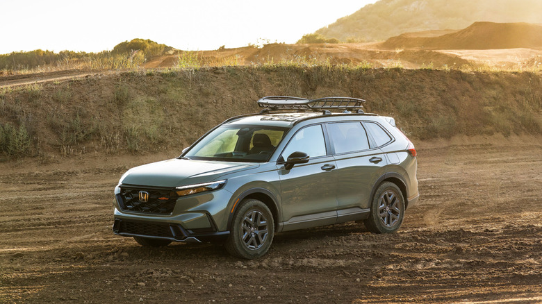 Green 2026 Honda CR-V TrailSport SUV Seen from left front three-quarter view parked on a dusty landscape in evening light