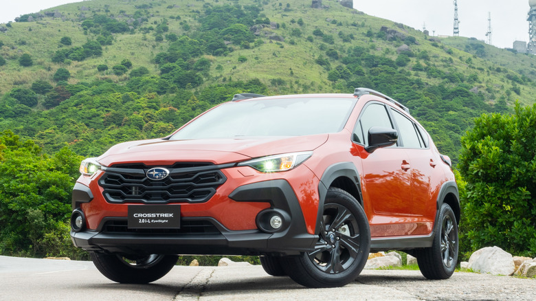 The front-left 3-4 of an orange 2023 Subaru Crosstrek parked in front of a hill