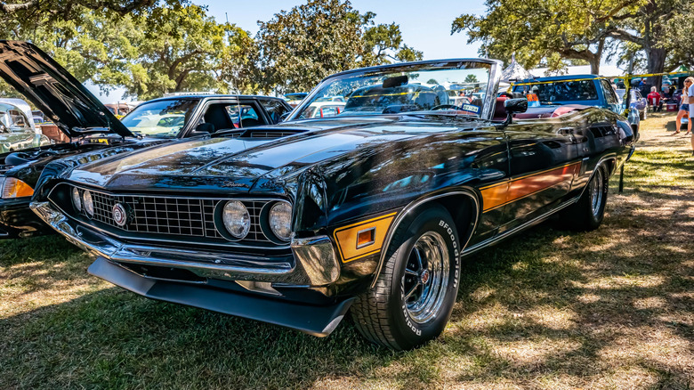 Stock image of a convertible Ford Gran Torino at a car show.