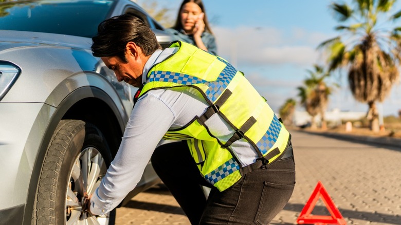 Roadside assistance tech changing customer's tire