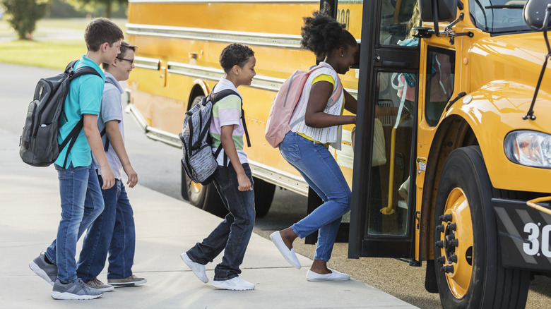 A group of young kids getting on a school bus
