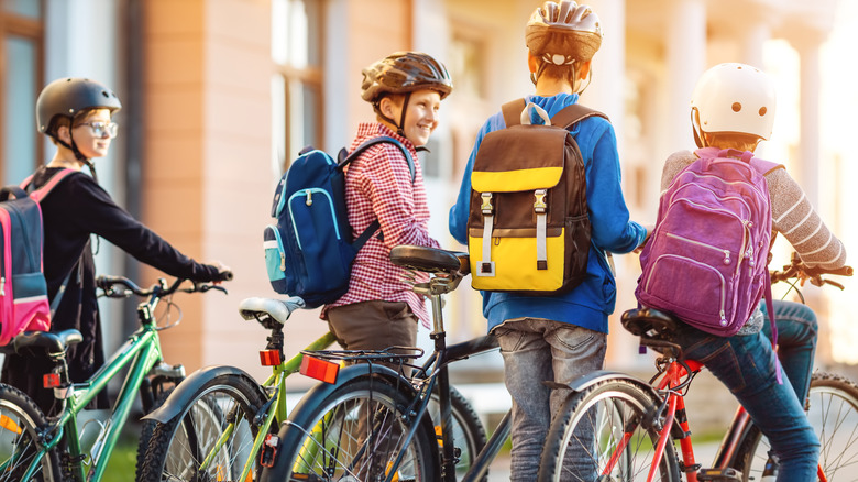 A group of four kids with backpacks and bikes