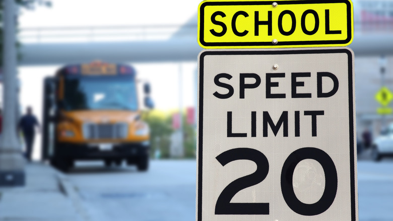 A school speed limit sign with bus in background