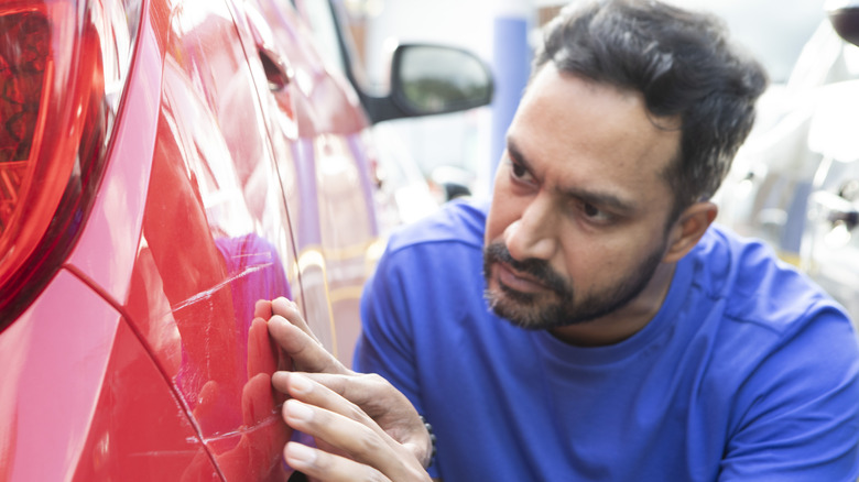 A buyer inspecting a car's damaged bodywork