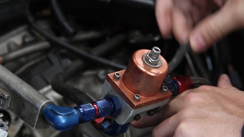 A person showing the vacuum hose coming from fuel pressure regulator to inlet manifold