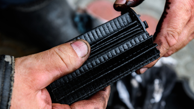 A mechanic checking an oil filter for metal shavings