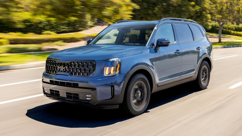 A blue 2025 Kia Telluride driving at speed