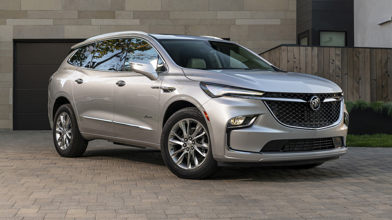 The front 3/4 view of a 2025 Buick Enclave Avenir parked in front of a building
