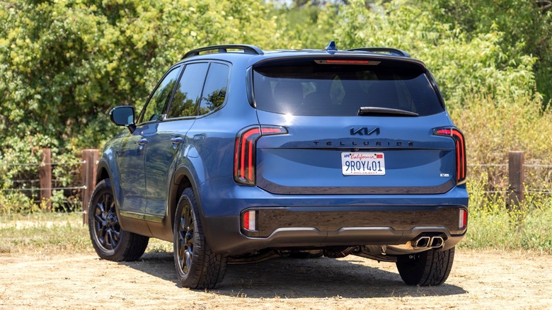 A rear left 3/4 of a dark blue Kia Telluride midsize SUV