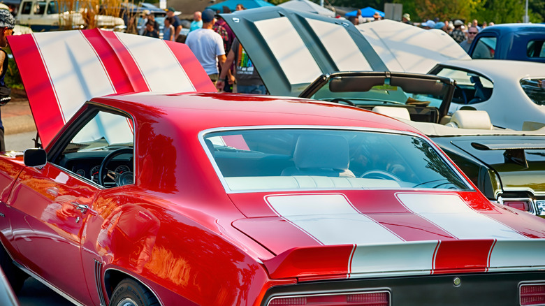 A lineup of classic American muscle cars at an outdoor car show.
