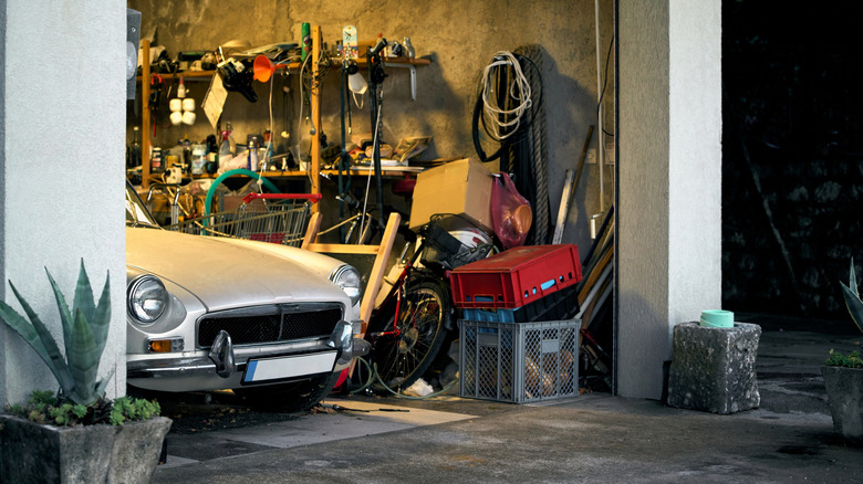 The nose of a classic, white MG sports car, parked in a slightly messy home garage.