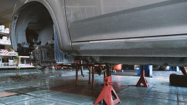 A gray car sitting on jack stands with the wheels and tires removed