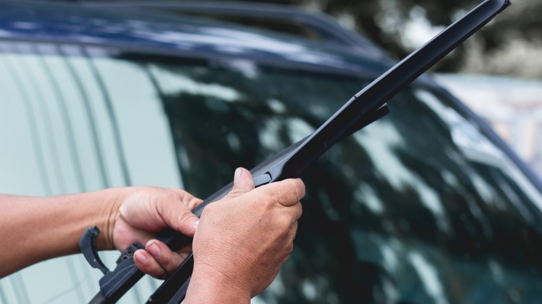 A person removing a car's windshield wiper blade
