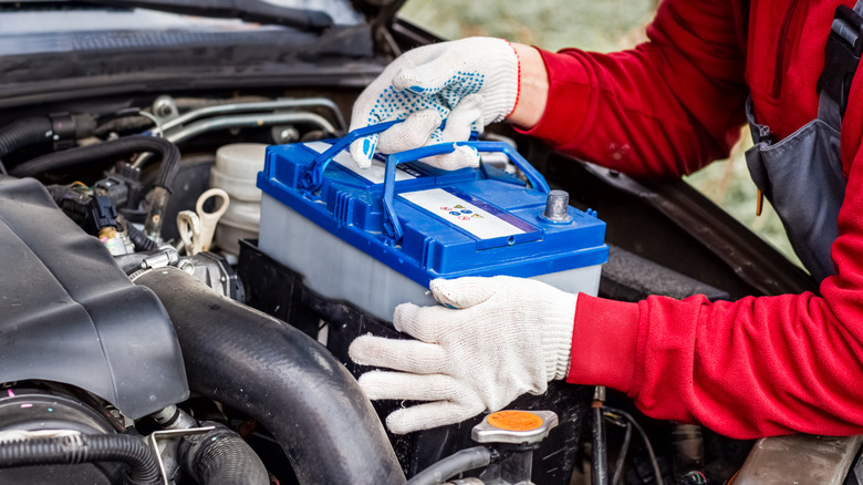 Mechanic placing car battery inside vehicle