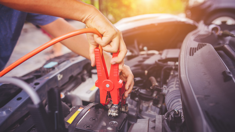 Mechanic placing jumper cable on battery.