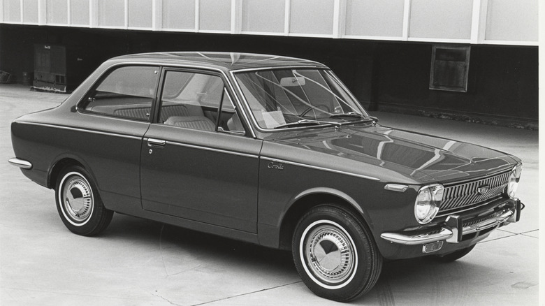 A 1969 Toyota Corolla in front of a building.