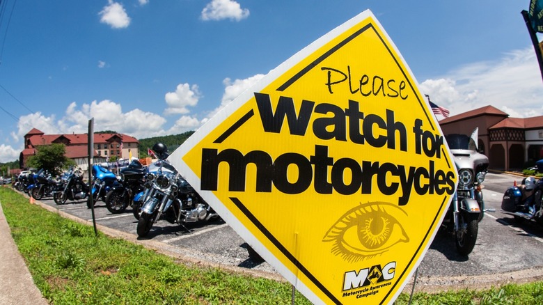 A yellow sign reminding drivers to watch for motorcycles