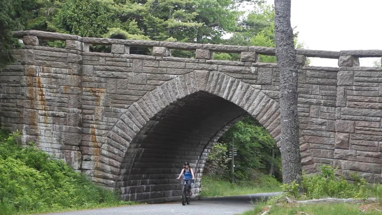 A bicyclist coming out from under a Rockefeller bridge in Acadia National Park