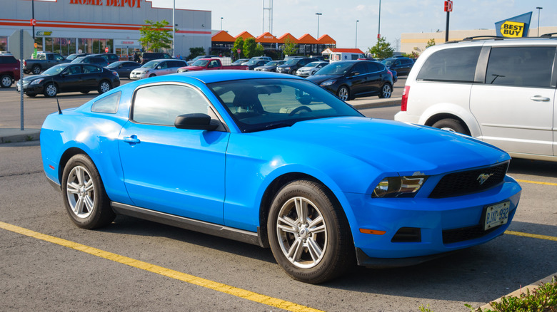 A 2007 blue Ford Mustang parked in a lot near a Home Depot and Best Buy.