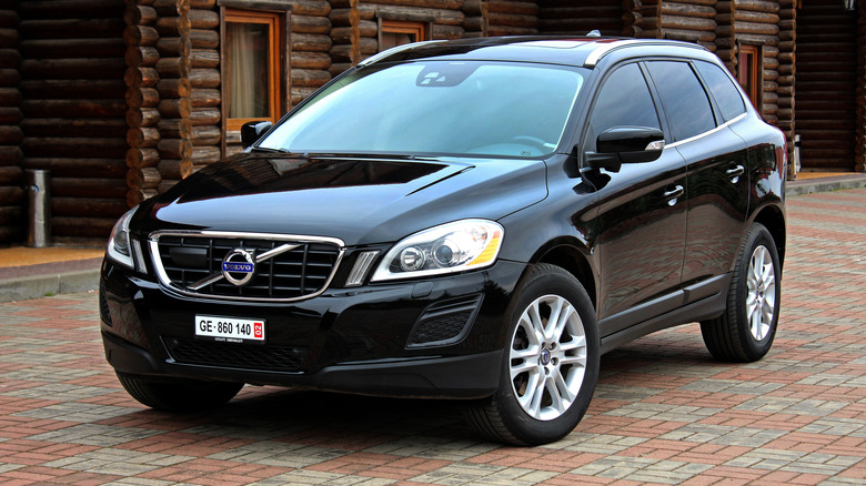 A black 2012 Volvo XC60 parked by wooden buildings.