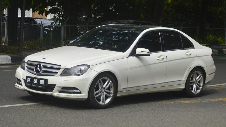 A white Mercedes W204 on a road.