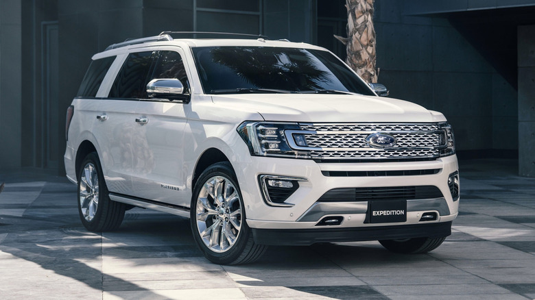 A white 2018 Ford Expedition parked on a paved surface in front of a building