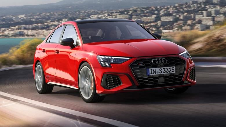 2022 Audi S3 driving up a coastal road with buildings and a body of water in the background