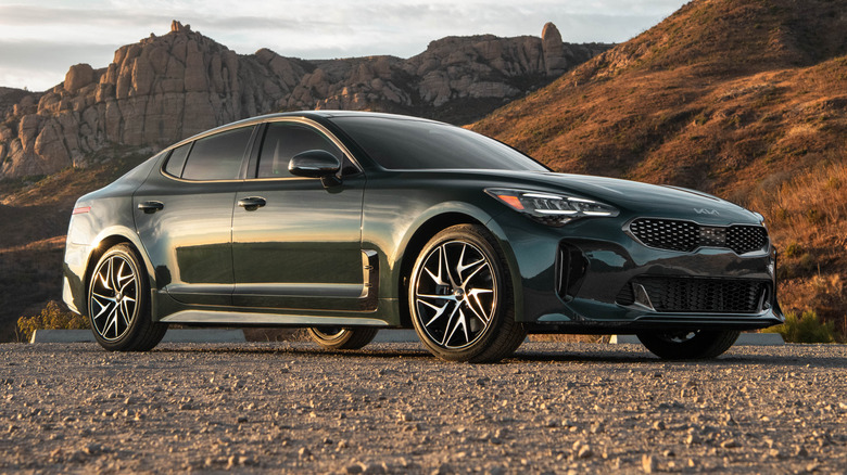 2023 Kia Stinger parked on a rocky dirt surface with mountains in the background