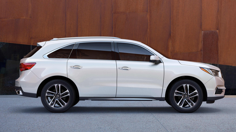 A white 2017 Acura MDX in front of a brown wall.
