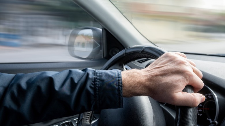 Hand on steering wheel turned to the right