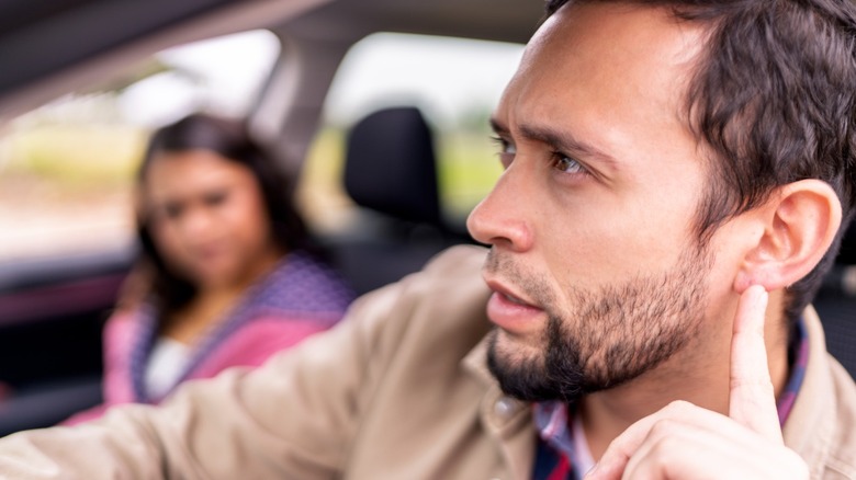 Male driver listening to noises from his car