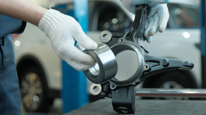 A gloved pair of hands placing a wheel bearing into a hub assembly