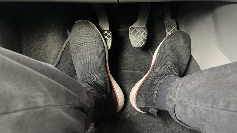 A close-up of a driver engaging the clutch pedal and the accelerator.