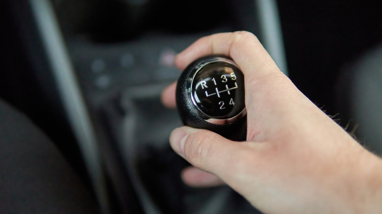 A close-up of a person holding a manual transmission lever.