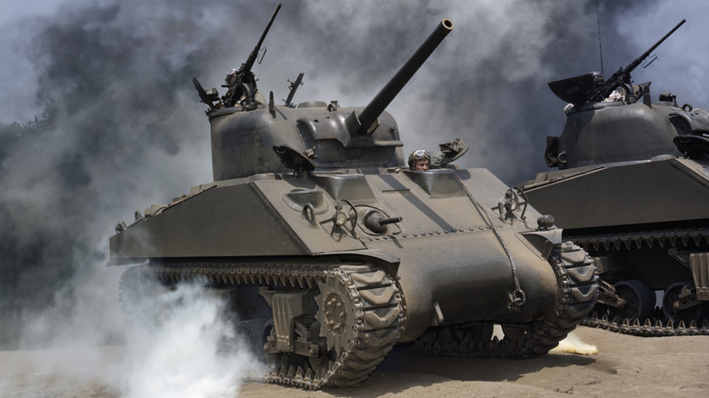 A set of M4 Sherman medium tanks at a reenactment, surrounded by smoke.