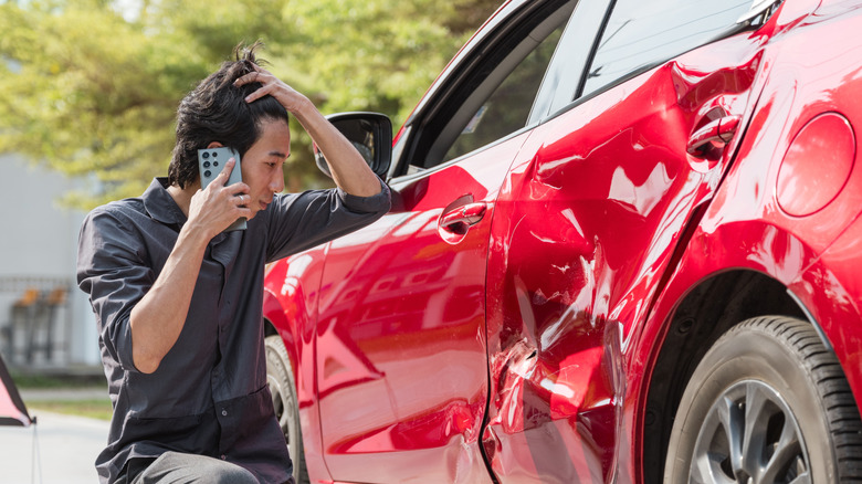 A person calling to make an insurance claim on a red car