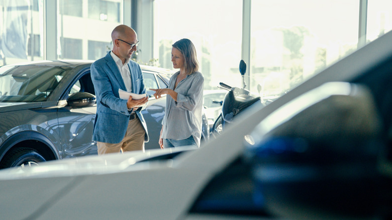 A happy customer buying a new car with salesperson