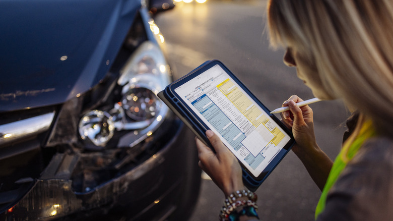 A person filling out a claim on a car insurance report